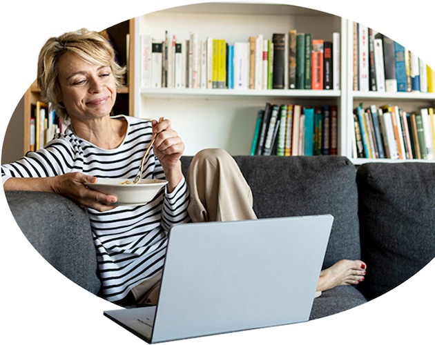 一个女人一边吃早餐一边放松，一边用笔记本电脑和她的经纪人聊天.