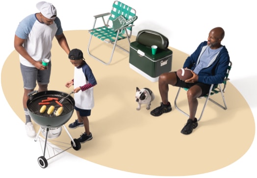 从上面看，父亲和儿子在烤热狗和玉米棒子，邻居和他的狗在附近的草坪椅子上监督.