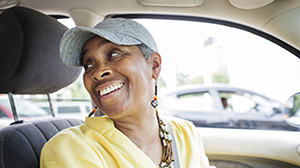 Woman turning to look at her passenger in the back of her car.