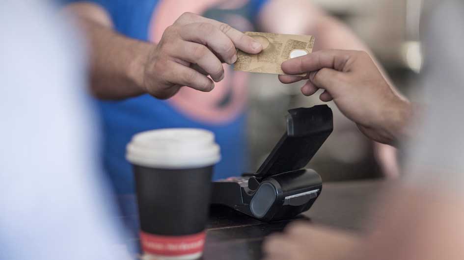 Someone hands over a credit card as a payment for coffee