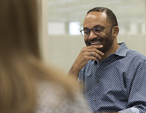 Image of man of minority ethnicity smiling at a meeting