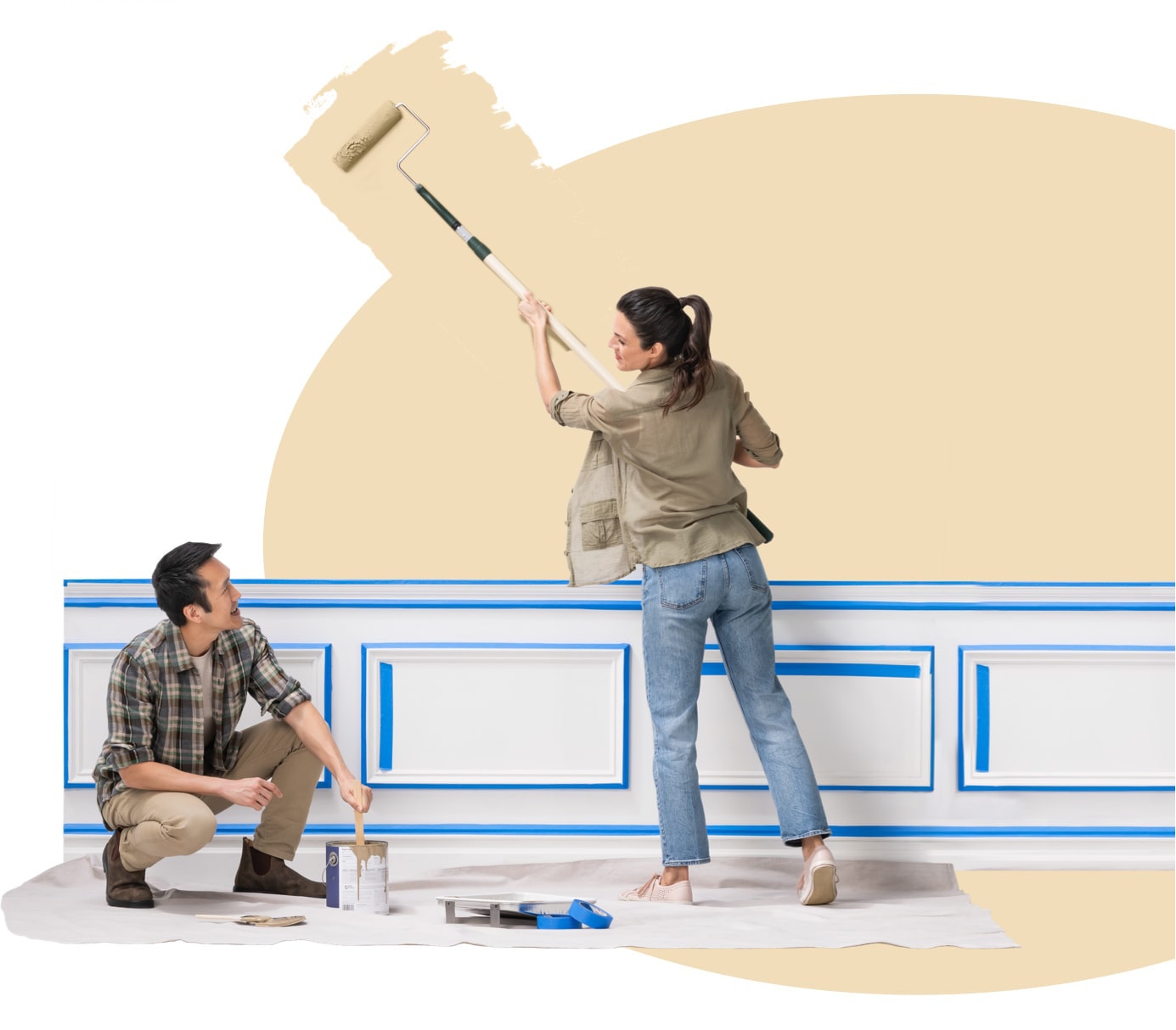 Woman paints outside the khaki oval with an extended roller as her husband takes on the wall moulding.