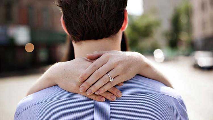 Hands with engagement ring embracing man