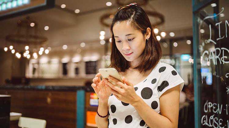 Woman looking at smartphone and accessing her files stored in the cloud