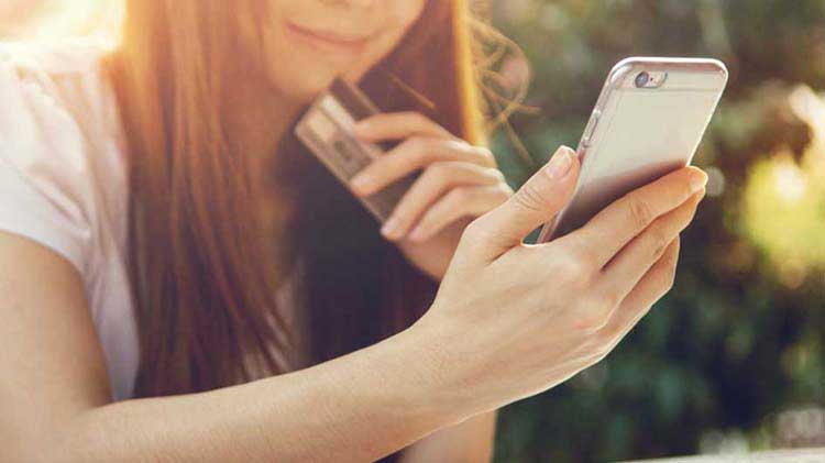 Woman with credit card looking at smartphone