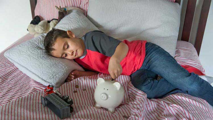 Boy on bed with his piggy bank