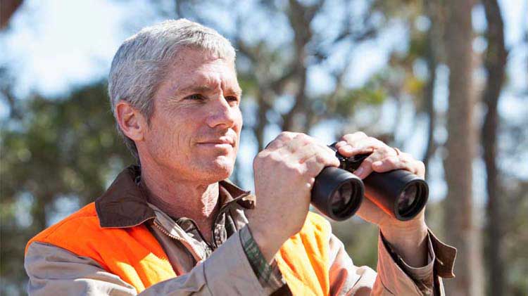 Hunter with orange vest and binoculars.