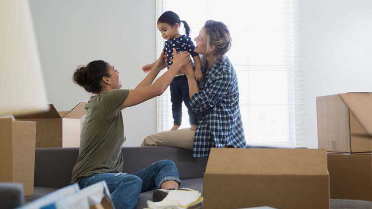 Two women and a little girl playing in a room full of moving boxes