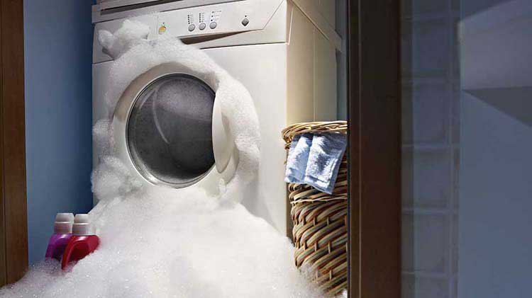 A washing machine is overflowing with soapy water.