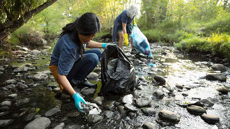 Two people donating their time to clean up trash in a stream.