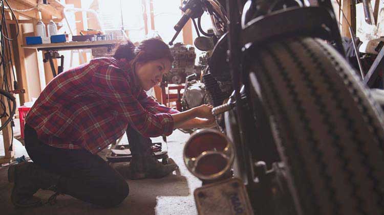 Woman working on motorcycle in a garage