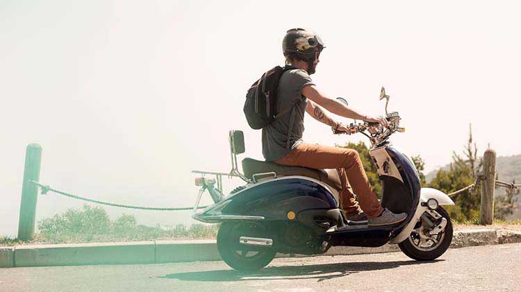 Man in helmet riding scooter.