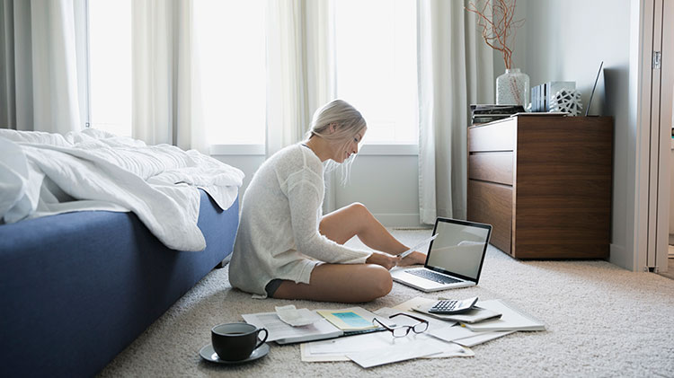Woman still on the floor with her bills and computer in front of her.
