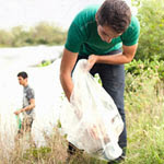 Adolescente recogiendo basura en un río.