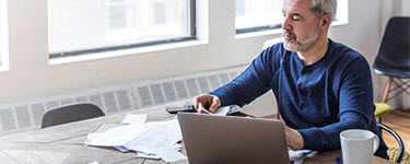 Man drinking coffee and paying bills in his apartment