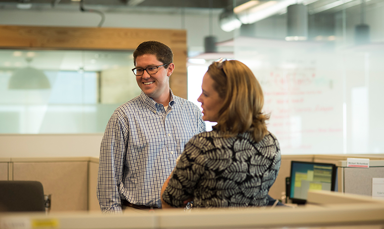 Man and women discussing work between cubes