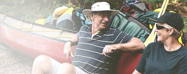 Senior couple relaxing beside canoe