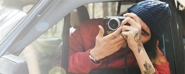 Man in a car with a camera taking a picture