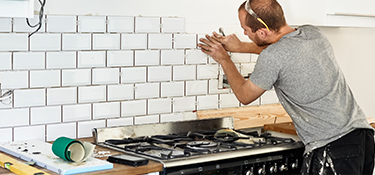 A man setting tile in a new kitchen