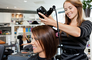 Hair stylist blowing drying clients hair