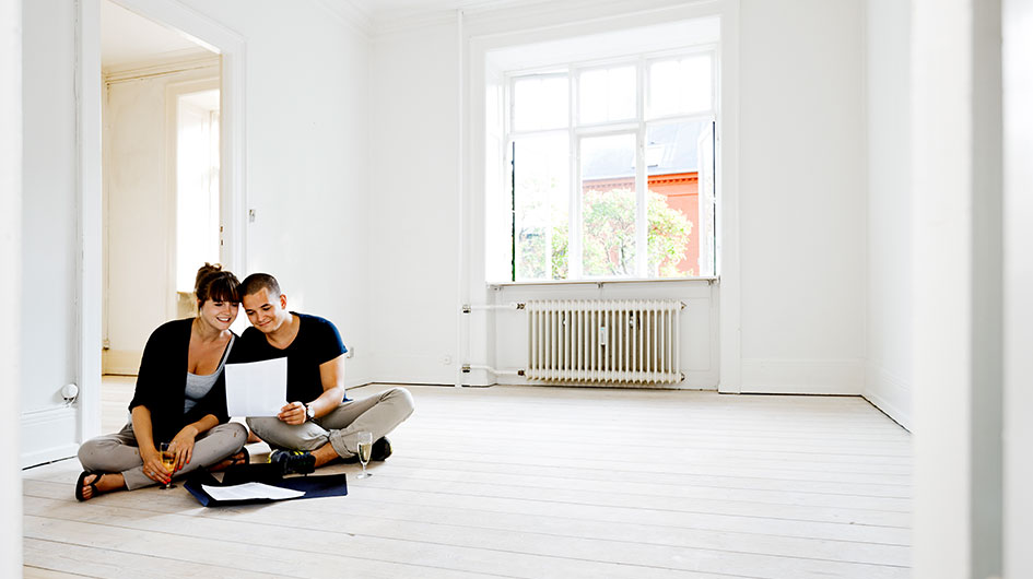 Couple sitting on the floor looking at a paper