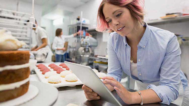 Propietaria de una panadería revisa planes de jubilación para pequeñas empresas en un iPad.