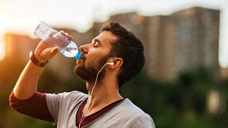 Athletic man outside drinking water