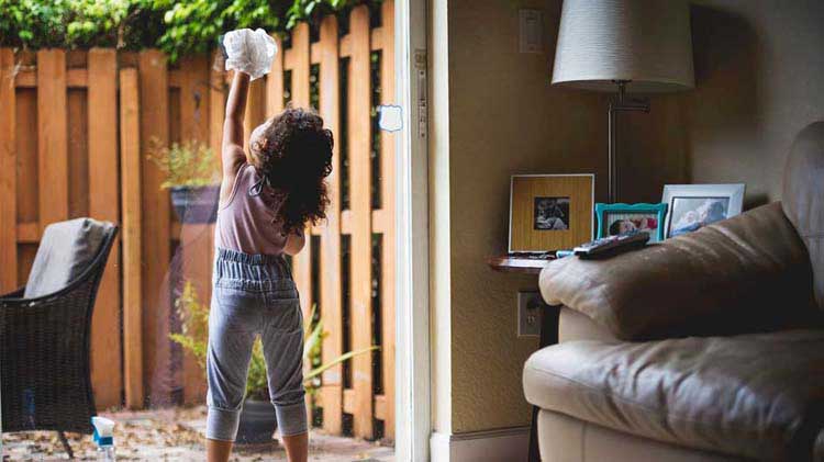 Little girl cleaning a glass sliding door