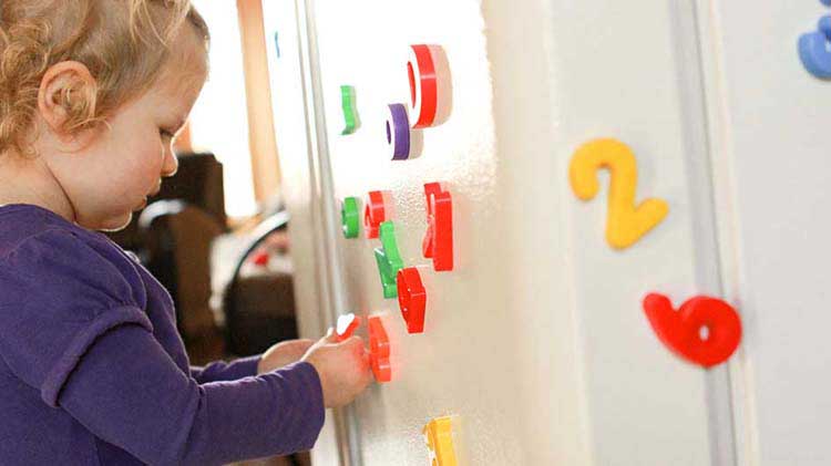 Toddler playing with refrigerator magnets