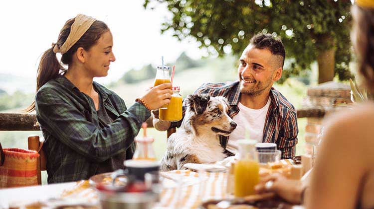 A man and woman at a house party are toasting with their drinking glasses