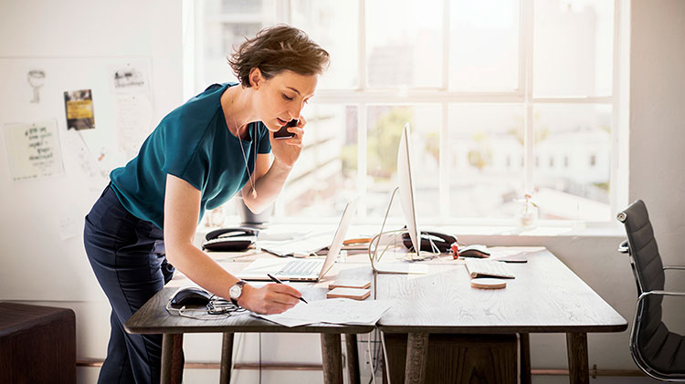 Woman working at a desk and talking on the phone.