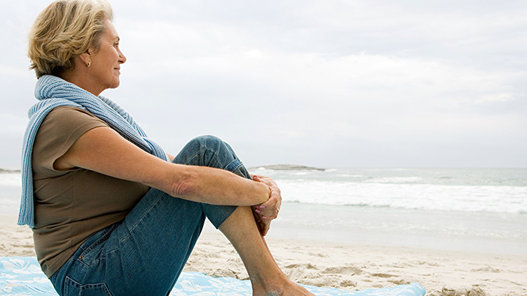Mujer sentada en la playa considerando la jubilación para mujeres
