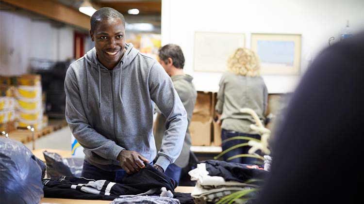 Man volunteering by packing clothes.