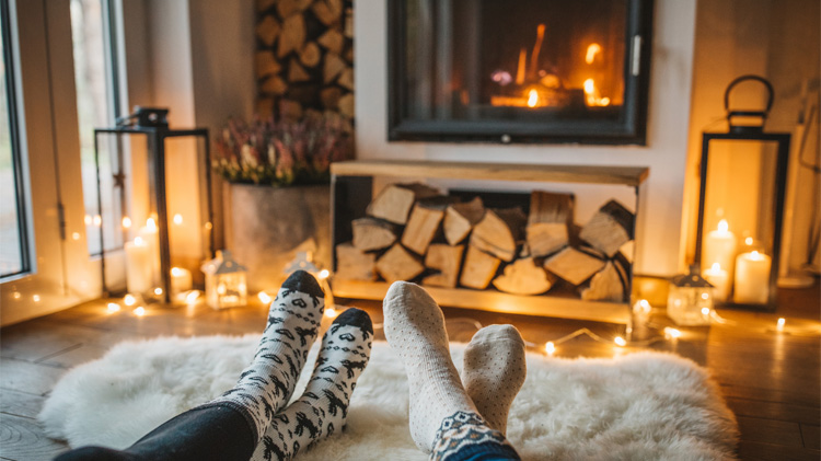 Una pareja en calcetines se sienta y disfruta de su chimenea.