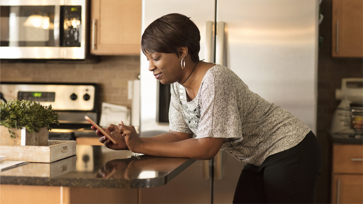 Una mujer usando el teléfono celular inteligente para escoger comunicaciones digitales